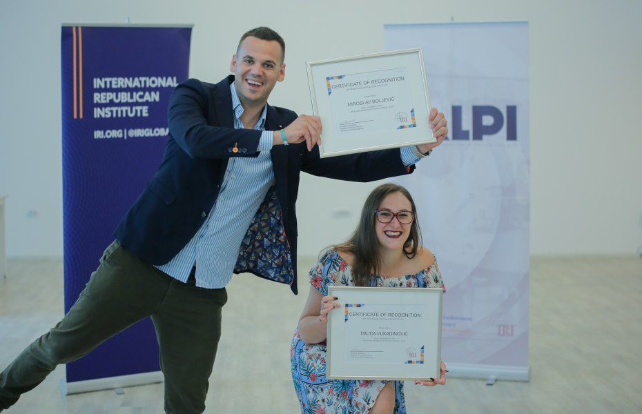 Two people hold up certificates