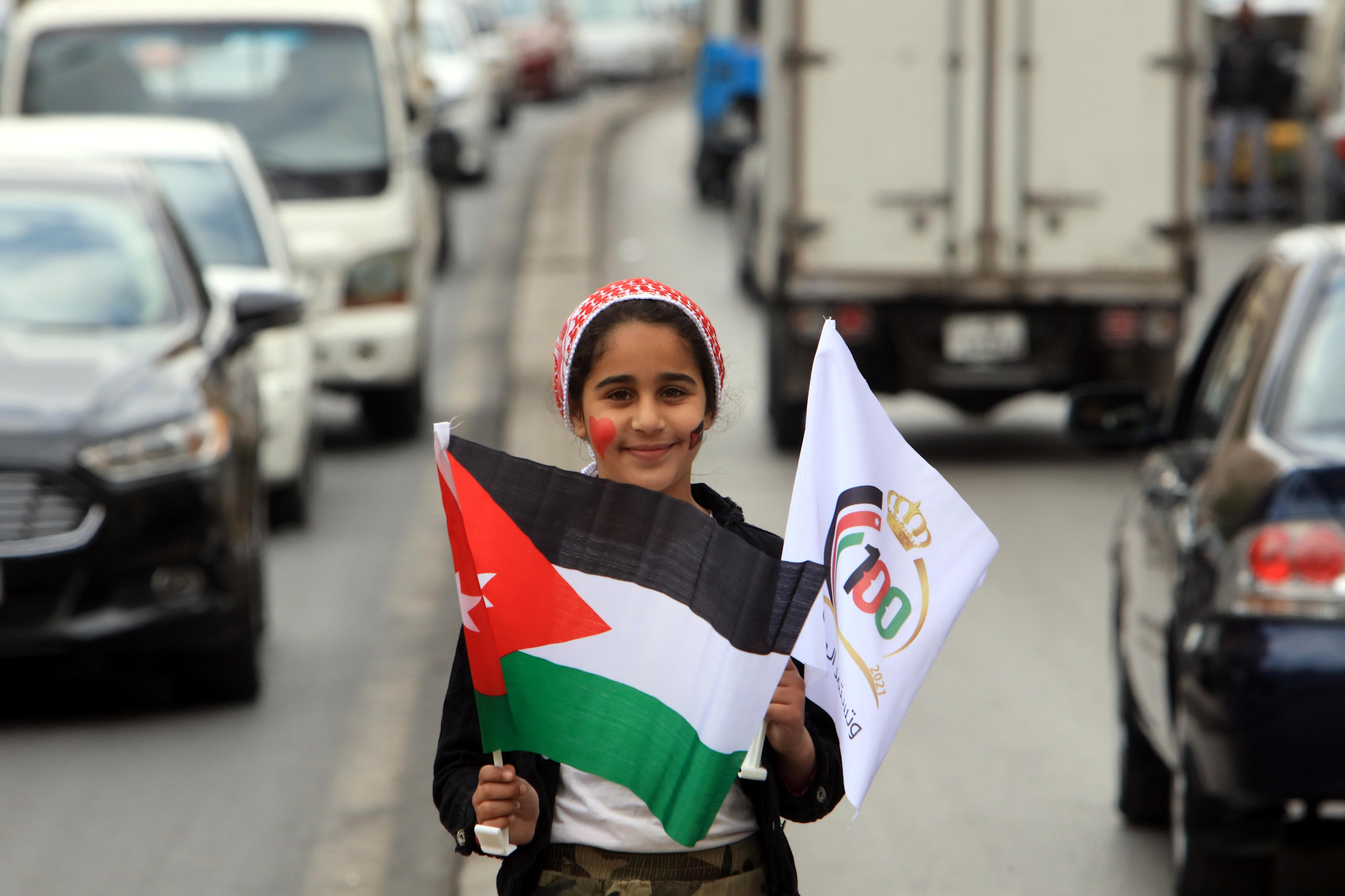 A girl holds a Jordanian national flag